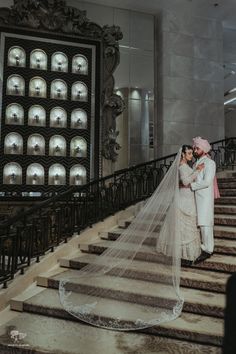 a bride and groom standing on some stairs