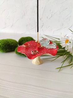 a red umbrella sitting on top of a table next to some grass and flowers in the background