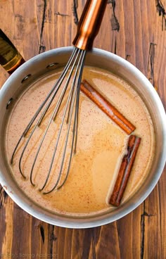 a bowl filled with batter and whisks on top of a wooden table