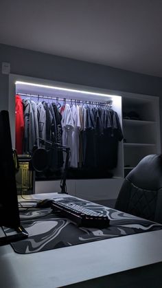 a desk with a laptop computer on it and clothes hanging in the closet behind it