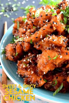 a blue plate topped with meat covered in sesame seeds and garnished with green onions