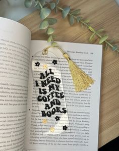 an open book with a tasseled keychain that says, all i need is coffee and books