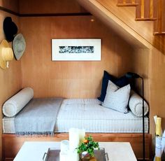 a bed sitting under a wooden staircase next to a table