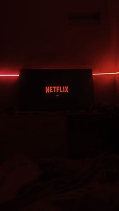 a red neon sign that reads netflix on it in the middle of a dark room