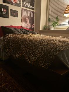 a leopard print comforter on a bed in front of a window with pictures above it