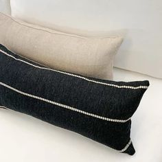 two black and white pillows sitting on top of a bed next to eachother