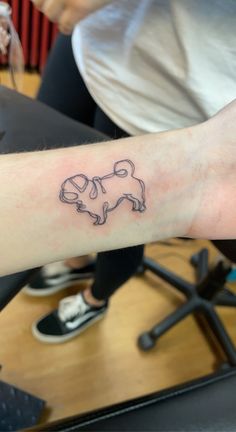 a person with a tattoo on their arm that has an outline of a dog in the shape of a heart