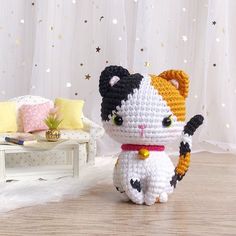 a crocheted cat sitting on top of a wooden floor next to a couch