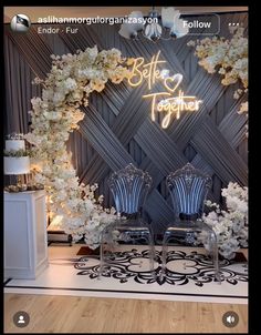 two chairs sitting next to each other in front of a wall with flowers on it