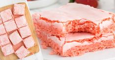 two pieces of pink cake sitting on top of a white plate next to a cutting board