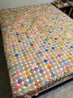 a bed with a multicolored bedspread on top of it in a room