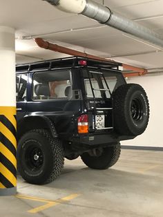 a black jeep parked in a parking garage next to a yellow and white striped pole