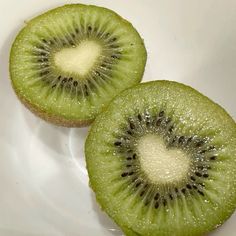 two slices of kiwi fruit sitting on top of a white plate next to each other