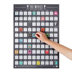 a hand is writing on a calendar with the words'100 movies'in it