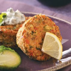 two crab cakes on a plate with cucumber and sour cream