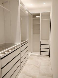 an empty walk - in closet with white cabinets and drawers