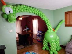 an inflatable balloon shaped like a green dinosaur is on the living room wall