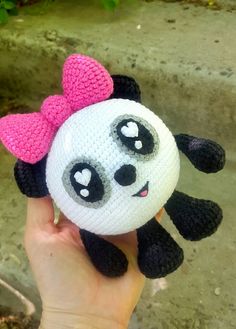 a hand holding a stuffed panda bear with a pink bow on it's head