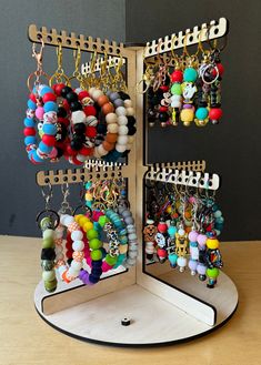 a wooden stand holding several different types of earrings and bracelets on it's sides