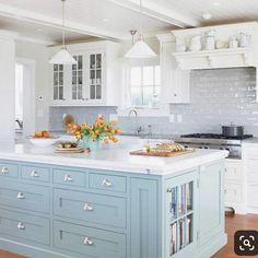 a kitchen with white cabinets and blue island