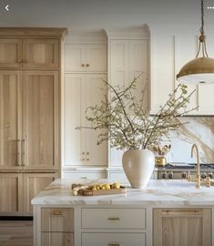 a large kitchen with marble counter tops and wooden cabinetry, along with a vase filled with flowers