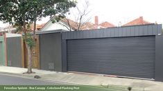 a grey garage door on the side of a house with trees and houses in the background