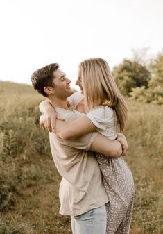 a man and woman hug each other in the middle of a field