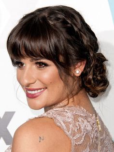 Michele's braided updo perfectly complements her face-framing bangs. Apply a volumizing mousse, like Kérastase Resistance Volumactive Mousse, and blow hair dry with a large round brush, Urban says. Part hair in the center and French braid a one-inch section, starting at the top of the head and wrapping behind the ear. Secure with an elastic. Sweep the rest of the hair into a low ponytail. Tease the ponytail before twisting into a bun and securing with U-shaped pins. Then, wrap in the braid and k Wedding Hair Bangs, Blow Hair, Braided Chignon, Braided Bangs, Hair Styles 2017, Crown Braid, Winged Liner, Penteado Cabelo Curto, Formal Hairstyles