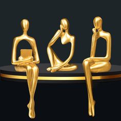 three golden statues sitting on top of a black table