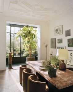 a table with four chairs and a potted plant on it in front of a window