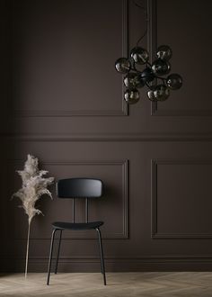 a black chair sitting next to a chandelier in a room with dark walls