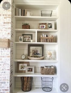 a white book shelf with baskets and pictures on it