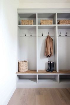 a white coat rack with two coats hanging on it's sides and some boots next to it