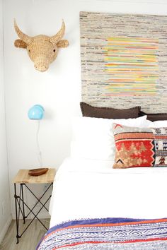 a bed with white sheets and pillows in a bedroom next to a wall mounted animal head