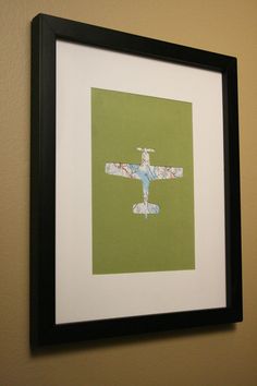 an airplane is mounted on the wall above a black framed art print with green background