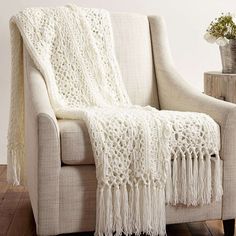 a white crocheted afghan sitting on top of a chair