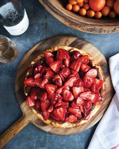 there is a pie with strawberries on it next to some oranges and wine