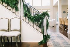 a staircase decorated with greenery and white ribbon for the holiday season is seen in this image