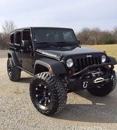 a black jeep is parked in the gravel