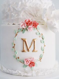 a wedding cake decorated with flowers and the letter m