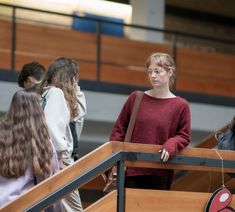 two women are standing at the top of a stair case in a building with wooden railings