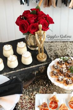 desserts and pastries are displayed on a table with red roses in the background