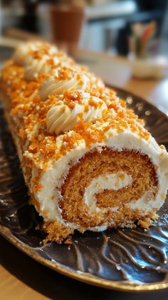 a piece of carrot roll on a plate with white frosting and orange sprinkles