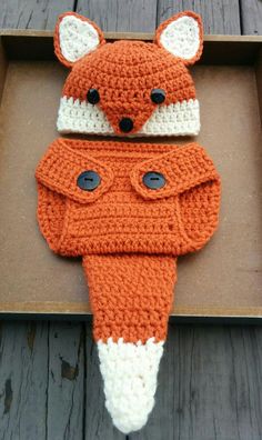 two crocheted fox hats and scarfs are sitting on a wooden surface next to each other