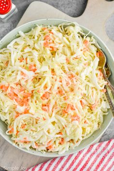 coleslaw in a bowl with a spoon on the side and red striped napkin next to it