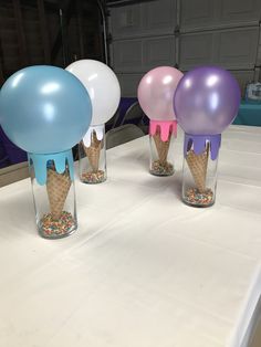 three ice cream cones in vases with balloons