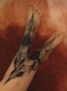 a woman's leg with tattoos on it and an egyptian bird flying above her