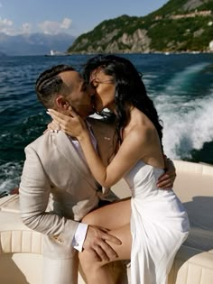 a man and woman kissing on the back of a boat