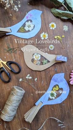 paper flowers and scissors on a table with twine spools for stringing