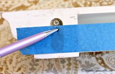 a purple pen sitting inside of a white box with blue tape on the top and bottom